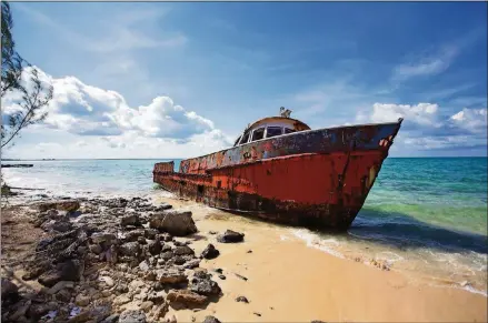  ?? BRILEY/ FOR THE WASHINGTON POST PHOTOS BY JOHN ?? A corroding fishing boat, abandoned after its captain passed away, sits on a beach in Exuma Sound on Cat Island, Bahamas.