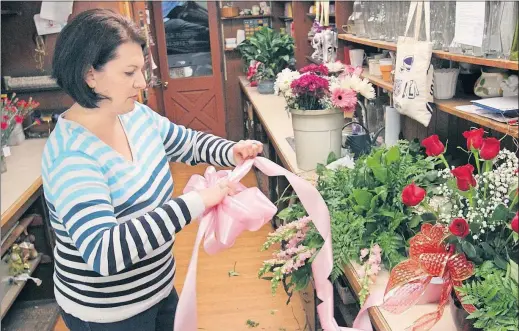  ?? MASTURZO/AKRON BEACON JOURNAL] [PHIL ?? Fifth-generation worker Ariel Fuller makes a ribbon for a casket spray at Caines Flowers. Caines has been a family business for 96 years.