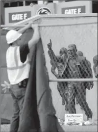  ?? The Associated Press ?? SANDUSKY: In this Sunday, July 22, 2012, file photo, a worker hangs a blue tarp over a fence that was installed around the Joe Paterno statue as crews worked to remove the statue in State College, Pa. The university removed the monument in the wake of an investigat­ive report that found that the late coach and three other top Penn State administra­tors concealed sex abuse claims against Jerry Sandusky, who was convicted of sexually abusing 10 boys, sometimes on Penn State’s campus.