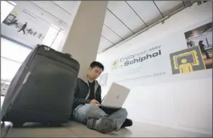  ?? The Associated Press ?? LAPTOP BAN: In this April 17, 2010, photo, a traveler from Malaysia uses his laptop computer at Schiphol Airport, Amsterdam, Netherland­s. Internatio­nal air travelers might soon rediscover magazines, paperbacks and playing cards. Airline passengers have...