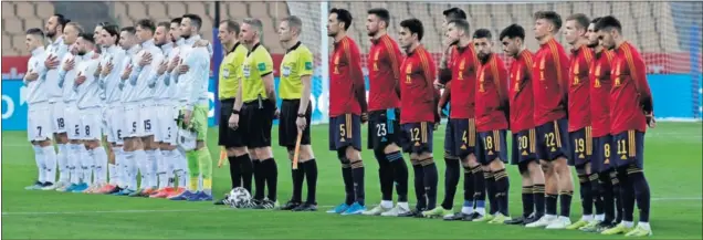  ??  ?? Los jugadores de Kosovo, que jamás se habían enfrentado a España, se tocan el escudo mientras escuchan en La Cartuja su himno nacional.