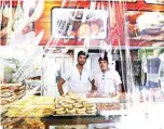  ??  ?? (From left to right) Iranian bakers Hasan, 17, and Mohsen, 23, pose behind a plastic sheet to protect their products, at their bakery in Tehran.