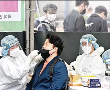  ?? AFP ?? A medical worker takes a nasal swab sample from a man at a Covid-19 coronaviru­s testing centre in Seoul on Thursday, after South Korea’s daily infections rose sharply to hit a new high of over 600,000.