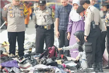  ??  ?? Next of kin attempt to identify personal items of loved ones who were on board the ill-fated Lion Air flight JT 610, at a port in Jakarta.