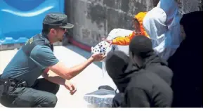  ??  ?? Kind gesture: A Spanish civil guard giving his daughter’s stuffed toy to a migrant child arriving on a boat at the port of Tarifa, Spain. — Reuters