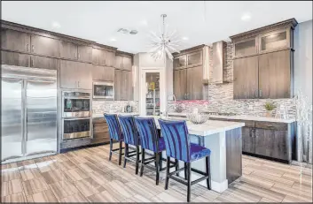  ?? Realty ONE Group ?? The kitchen features an island with seating, custom wood cabinetry, quartz countertop­s and profession­al-grade stainless steel appliances.