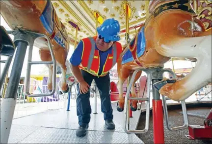  ?? THE ASSOCIATED PRESS ?? Amusement device inspector Avery Wheelock inspects the safety pins on a children’s merry-go-round at the Mississipp­i State Fair in Jackson, Miss., on Oct. 6, 2015. In some parts of the U.S., the thrill rides that hurl kids upside down, whirl them...