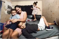  ?? AL DIAZ adiaz@miamiheral­d.com ?? Greila Javier de Benavides holds Erick, 1; Alexis, 6, is at front right, and Solimar Javier, 4, is in back. They are in the bedroom they share at their home in Miami.