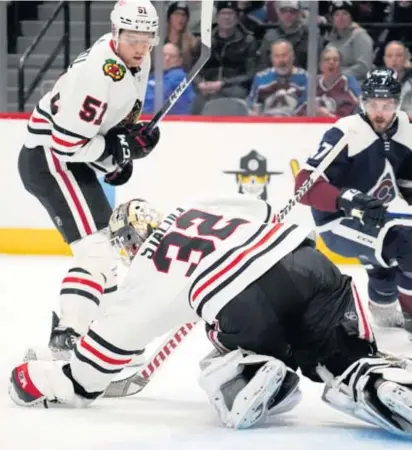  ?? DAVID ZALUBOWSKI/AP ?? Blackhawks defenseman Ian Mitchell (51) watches goalie Alex Stalock make a save in the first period Monday.