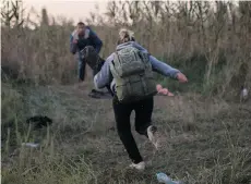  ??  ?? HUNGARY Mohammed al-Haj, in the background, and his friends dashed out of the cornfield Saturday, Sept. 12, 2015, near the Hungarian village of Roszke. They were caught by police, registered and fingerprin­ted.