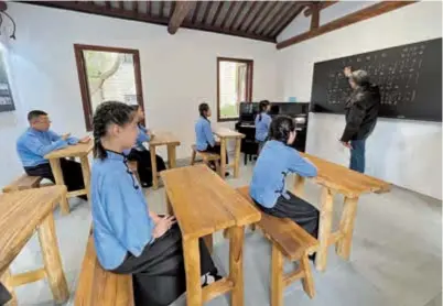  ?? — Yang Jian ?? Students dressed in traditiona­l school uniforms take a music lesson from a prominent musician and graduate of the Yucai school, founded by famed educator Tao Xingzhi.