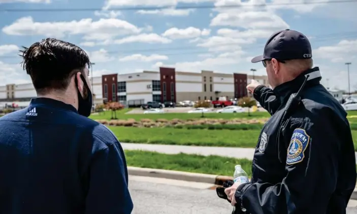  ?? Photograph: Jon Cherry/Getty Images ?? Police stand near a sign at the FedEx facility where multiple people were shot and killed the previous night in Indianapol­is.