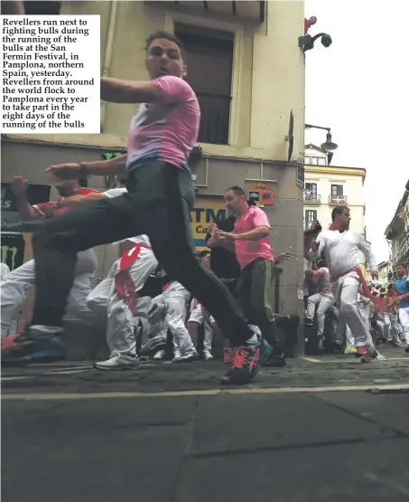  ??  ?? Revellers run next to fighting bulls during the running of the bulls at the San Fermin Festival, in Pamplona, northern Spain, yesterday. Revellers from around the world flock to Pamplona every year to take part in the eight days of the running of the bulls