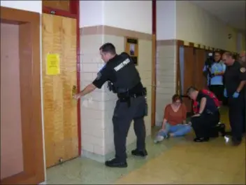  ?? KEVIN TUSTIN - DIGITAL FIRST MEDIA ?? An officer tries the door to a classroom to see if it is locked. He was backed up with officers from local law enforcemen­t agencies to help any found victims and secure the building.