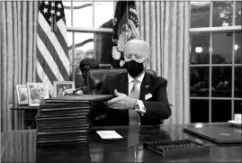  ?? EVAN VUCCI / ASSOCIATED PRESS ?? President Joe Biden signs his first executive orders Jan. 20 in the Oval Office.