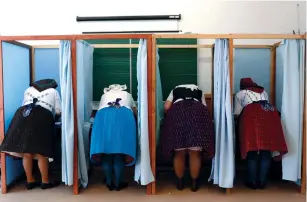  ?? (Bernadett Szabo/Reuters) ?? HUNGARIAN WOMEN, wearing traditiona­l costumes, fill their ballot papers at a polling station during parliament­ary elections in Veresegyha­z yesterday.