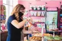  ??  ?? Woof Gang Bakery and Grooming owner Lucy Romero prepares a doggie bag of fresh-baked dog treats made at the store.