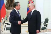  ?? ANTON NOVODEREZH­KIN, SPUTNIK, KREMLIN POOL PHOTO VIA AP ?? Russian President Vladimir Putin greets Chinese Communist Party foreign policy chief Wang Yi during their meeting at the Kremlin in Moscow on Wednesday.