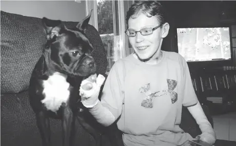  ?? JULIE OLIVER ?? Jonathan Pitre, shown at age 14, enjoys some playtime with his dog Gibson.