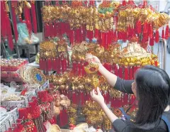  ?? PAWAT LAOPAISARN­TAKSIN ?? A woman chooses Chinese New Year decoration­s at a shop in Bangkok’s Chinatown. The UTCC forecasts 56.9 billion baht in spending to mark the holiday.