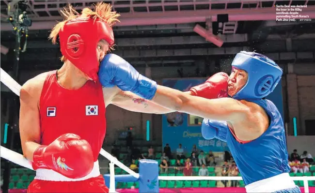  ?? AFP PHOTO ?? Sarita Devi was declared the loser in the 60kg semifinals despite pummelling South Korea’s Park Jina (red).