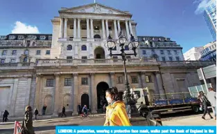  ??  ?? LONDON: A pedestrian, wearing a protective face mask, walks past the Bank of England in the City of London. — AFP