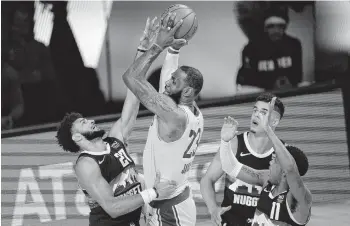  ?? MARK J. TERRILL/ASSOCIATED PRESS ?? The Los Angeles Lakers' LeBron James shoots against the Denver Nuggets' Jamal Murray, left, during the second half Thursday in Lake Buena Vista, Florida. The Lakers won 114-108 for a 3-1 series lead, and they can end the series tonight.