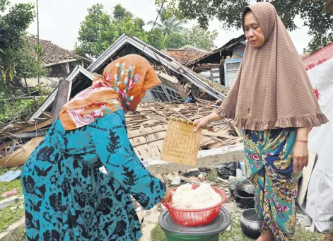  ?? ?? Women cook beside the rubble of a collapsed house in Cugenang, Cianjur, Indonesia, Nov. 23, 2022.