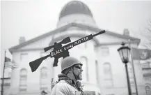  ?? Robert F. Bukaty / Associated Press ?? Joe Dobbins of Hartford, Maine, wears a cutout of an AR-10 tactical rifle while attending a gun rights rally with hundreds of others Saturday at the State House in Augusta, Maine.