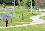  ?? Doug Walker ?? A woman uses the trail at Etowah Park near three of the 17 trees that will be dedicated Tuesday during a ceremony at 2:30 p.m. Tuesday. Internatio­nal Paper donated the trees to help compensate for the loss of trees to a new gas line through Ridge Ferry Park.