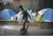  ?? Al Seib Los Angeles Times ?? JOHN GUNN leaps over the water at his tent on skid row where his belongings were soaked by rain.