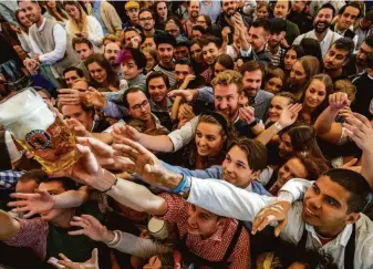  ?? Michael Probst / Associated Press ?? People reach for beer on the opening day of the 187th Oktoberfes­t in Munich. The festival did not take place in 2020 and 2021 as authoritie­s sought to contain the coronaviru­s pandemic.