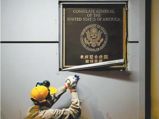  ??  ?? A worker removes the plaque at the US consulate in Chengdu this week. Reuters / Thomas Peter