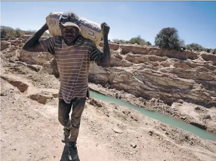  ?? JUNIOR KANNAH/AFP/GETTY IMAGES ?? A man carries a bag of copper at a mine quarry and cobalt pit in Lubumbashi, the second largest city in Democratic Republic of Congo, a key source of the sought-after mineral. Cobalt prices have surged at four times the pace of major metals in the past...