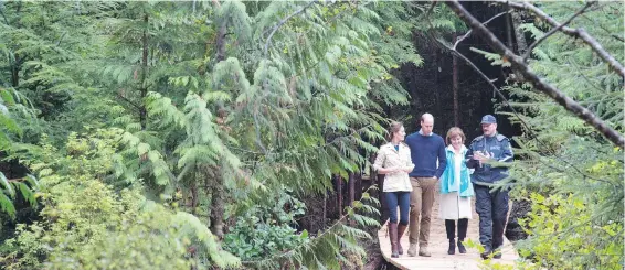  ??  ?? The Duke and Duchess of Cambridge, left, and Premier Christy Clark walk through the Great Bear Rainforest in Bella Bella on Monday.