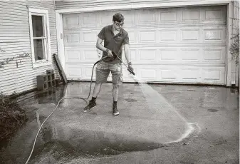  ?? Jon Shapley / Staff photograph­er ?? Scott Wessels power-washes his friend’s driveway and house late last month. When Wessels was laid off from an oil and gas job last year, he started a power washing company to make money.