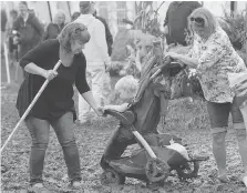  ?? DAVE CHIDLEY/THE CANADIAN PRESS ?? Erin Carnoghan, left, and her mother-in-law Leanne McKay struggle with one-year-old Paige in a stroller stuck in the mud on Tuesday at the Internatio­nal Plowing Match in Walton.