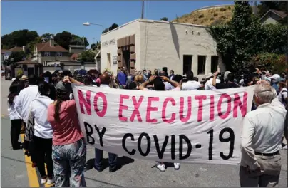  ?? The Associated Press ?? SAN QUENTIN STATE PRISON: People hold up a banner while listening to a news conference on July 9 outside San Quentin State Prison in San Quentin, Calif. One in five state and federal prisoners in the United States has tested positive for the coronaviru­s, a rate more than four times higher than the general population. In some states, more than half of prisoners have been infected, according to data collected by The Associated Press and The Marshall Project.