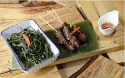  ??  ?? So-called morning glory stems, or water spinach, and grilled pork butt with dipping sauce are the kind of Thai/Laotian street foods served at this restaurant.