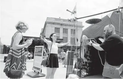  ?? CAITLIN FAW/BALTIMORE SUN PHOTOS ?? Aaron Pierce, the “Celestial Diplomat,” checks Laura Pierpont, 24, of Baltimore County for alien implants before she enters Moloch’s Institute for Extranorma­l Research, an Artscape exhibit that explores aliens and other abnormalit­ies.