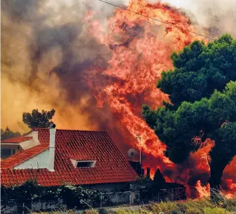  ??  ?? Una casa minacciata delle fiamme alte metri e alimentate dal forte vento a Kineta, vicino ad Atene