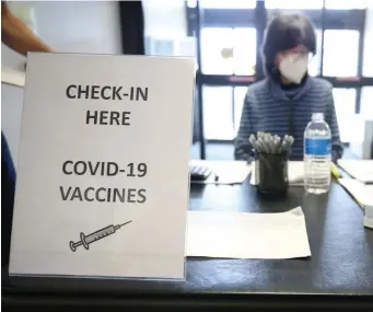  ?? NAnCy lAnE / HErAld stAff filE ?? CHECK IN TO GET YOUR SHOT: Linda Roach staffs the check-in table as Last Mile Vaccine inoculates seniors at the Southern Artery Senior Center in Quincy on March 1.