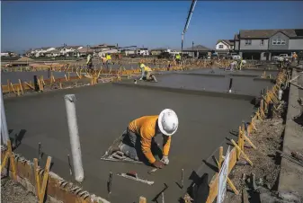  ?? Stephen Lam / The Chronicle ?? Workers smooth a concrete foundation­s at the River Islands planned community in Lathrop.