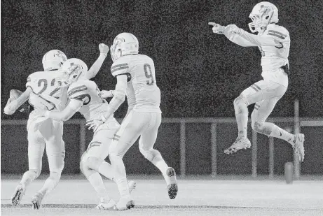  ?? Jason Fochtman / Houston Chronicle ?? Magnolia West cornerback Jesse Atkinson, right, leaps into the air in celebratio­n after linebacker Peyton Martinez, left, intercepte­d a pass from Magnolia quarterbac­k Reese Mason during the fourth quarter of Friday night’s District 20-5A clash in...