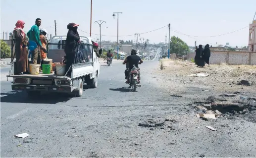  ?? (Alaa al-Faqir/Reuters) ?? PEOPLE RIDE on a truck yesterday near the site hit by an air strike in Muzayrib.