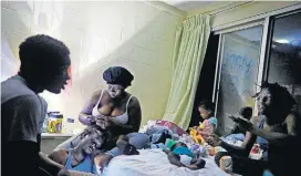  ?? [AP PHOTO] ?? Gabrielle Morgan, center rear, braids the hair of her husband, Santional, as they sit by a lantern with their children, from left, Decoya, 13, Isabella, 3 mos., Gabriella, 3, and Lakevia, 15, in their room at the damaged American Quality Lodge, where they continue to live without power in the aftermath of Hurricane Michael, on Tuesday in Panama City, Fla.