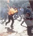  ?? AP ?? A South Korean student is engulfed in flames as his compatriot­s launch firebombs toward riot police during a demonstrat­ion in Seoul in 1988.