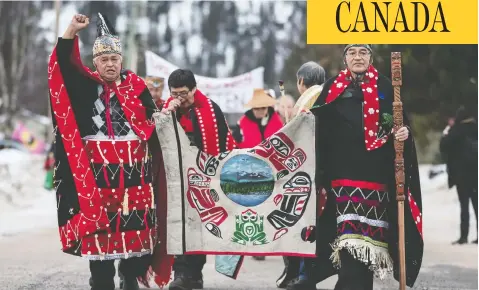  ?? DARRYL DYCK/THE CANADIAN PRESS ?? Chief Madeek (Jeff Brown), left, hereditary leader of the Gidimt’en clan, and Wet’suwet’en hereditary Chief Namoks (John Ridsdale), right,
carry a flag while leading a solidarity march for the Wet’suwet’en Nation, in Smithers, B.C., last January.