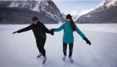  ??  ?? Australian tourists Laura Judd, left, and Paige Gilbert help each other navigate the bumpy ice on the frozen Lake Louise in Banff National Park, Alta.