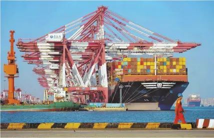  ?? STR/AFP/GETTY IMAGES; AP FILE PHOTO, BELOW ?? IMPORT-EXPORT: A cargo ship is seen yesterday at a port in Qingdao in China’s eastern Shandong province, above. Below, workers pull carts loaded with shoes along a street in Beijing in August.